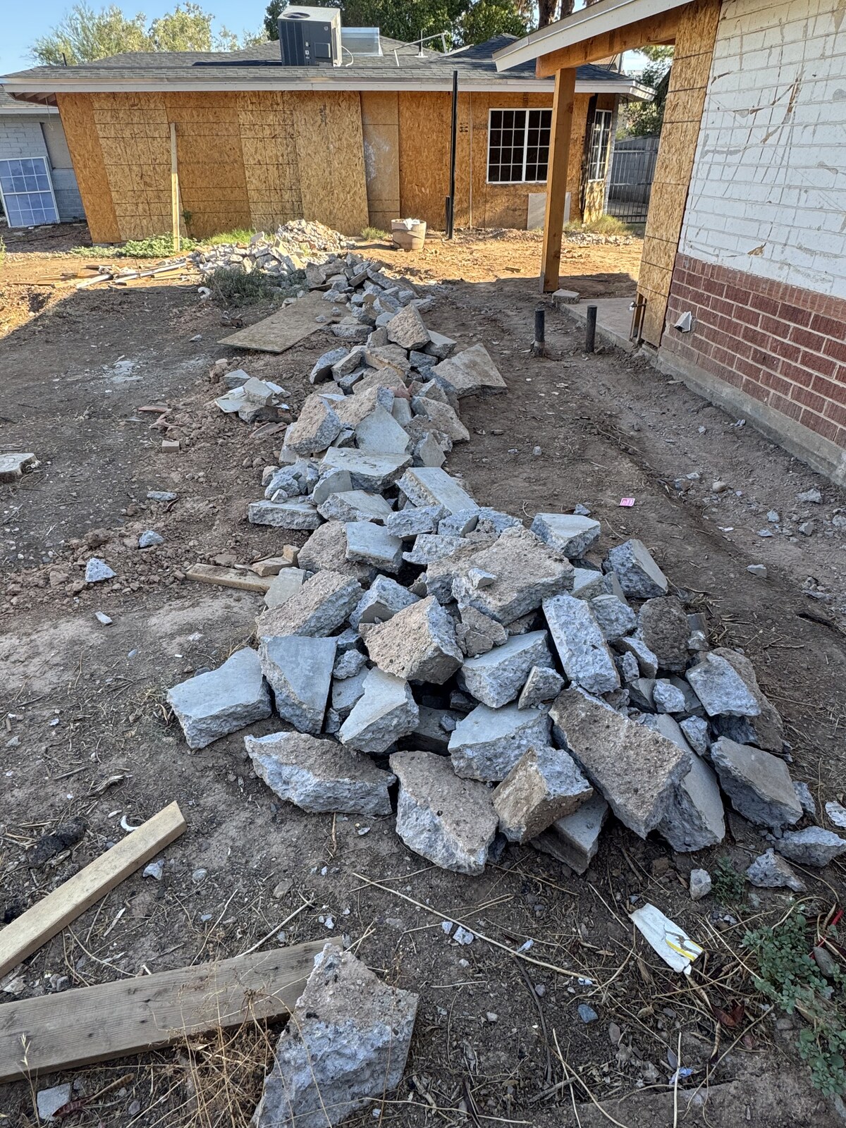 Broken concrete patio slab busted up into a pile of rubble in a backyard ready for haul-off
