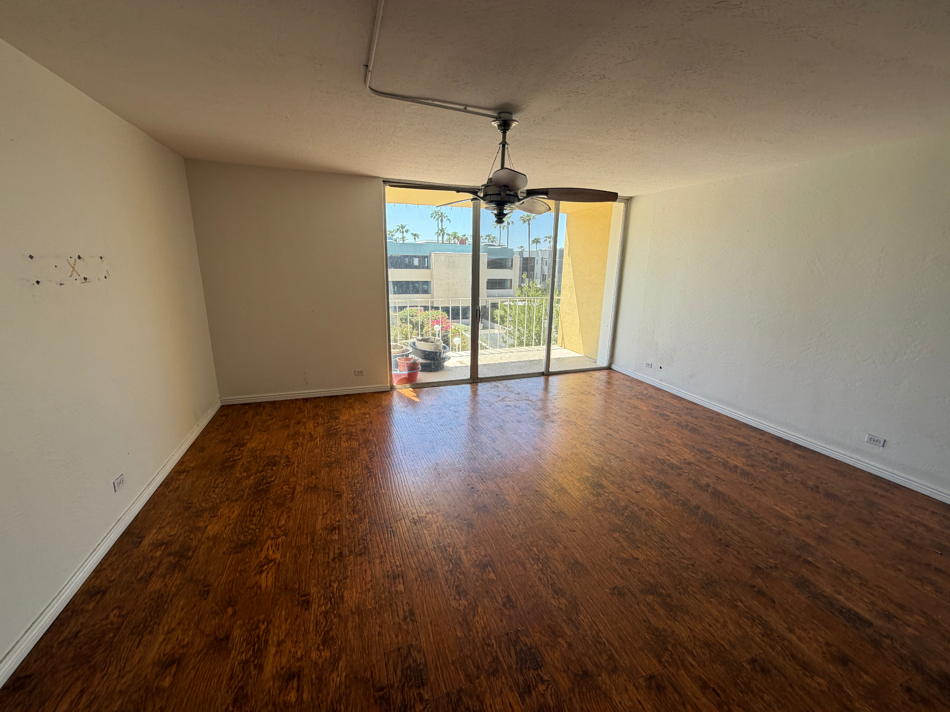 Empty condo living room with clean wood floors and a clear balcony doorway after all furniture and junk was hauled off
